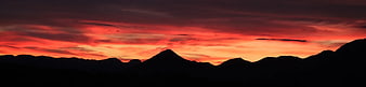 Dramatic red sunset silhouette over mountain range