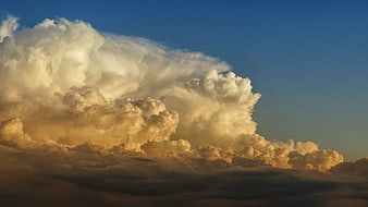 Dramatic golden cumulus clouds against deep blue sky