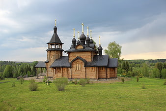 Traditional wooden Orthodox church with golden crosses in green landscape