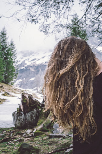 Woman with long wavy hair looking at snowy mountain landscape