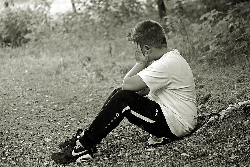 Sad Boy Sitting Alone in Forest Hiding Face
