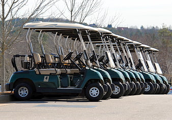 Row of green golf carts parked on asphalt
