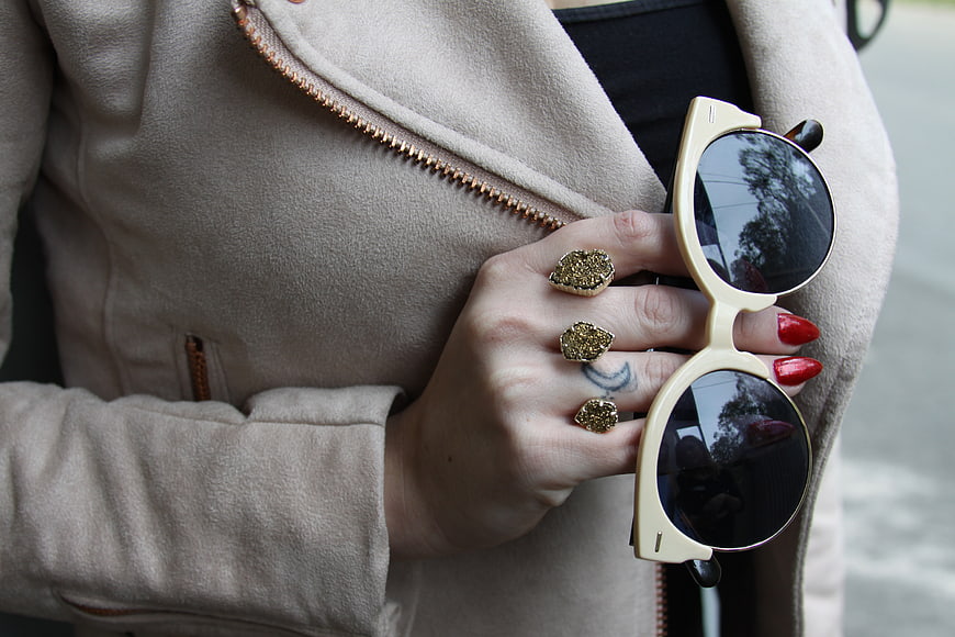 Woman's Hand Holding Sunglasses with Gold Rings