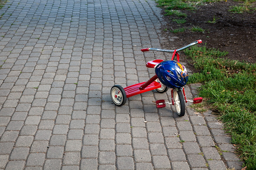 Red Tricycle with Blue Helmet on Paved Path