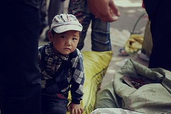 Portrait of young boy in cap sitting on yellow sack