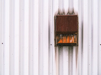 Rusty industrial vent on white corrugated metal wall