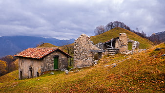 Abandoned stone ruins on a grassy autumn hillside with distant mountains