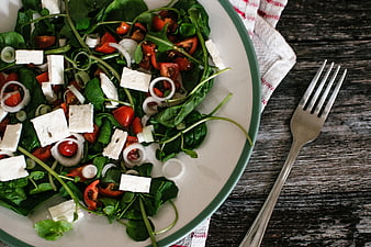 Fresh spinach salad with feta cheese and tomatoes on rustic wood