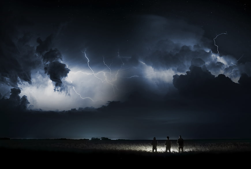 Three Silhouetted Figures Watching Lightning Storm at Night