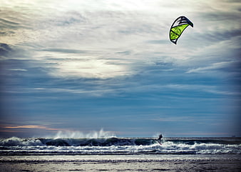 Kitesurfer riding waves on a dramatic cloudy ocean day
