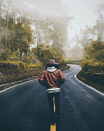 Man walking away on winding forest road