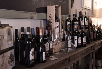 Wine bottles and glasses on rustic wooden shelf in shop