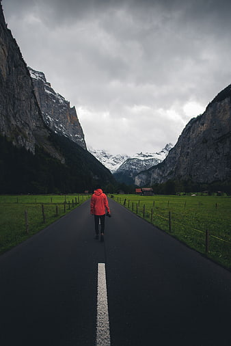Person in Red Jacket Walking on Mountain Road