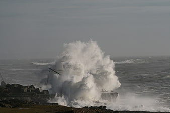 Powerful ocean wave crashing against rocky sea wall