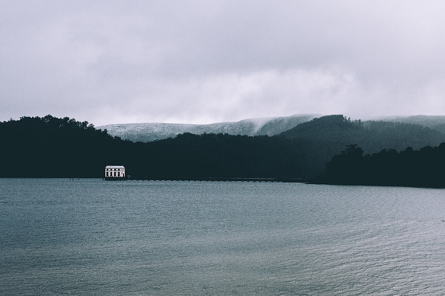 Misty Lake Landscape with White Pavilion and Forested Hills