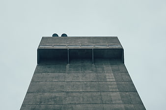 Low angle view of brutalist concrete tower against grey sky