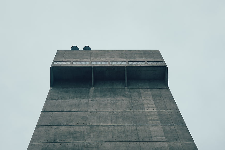Low angle view of brutalist concrete tower against grey sky
