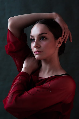 Elegant woman in red sheer blouse posing with hands behind head