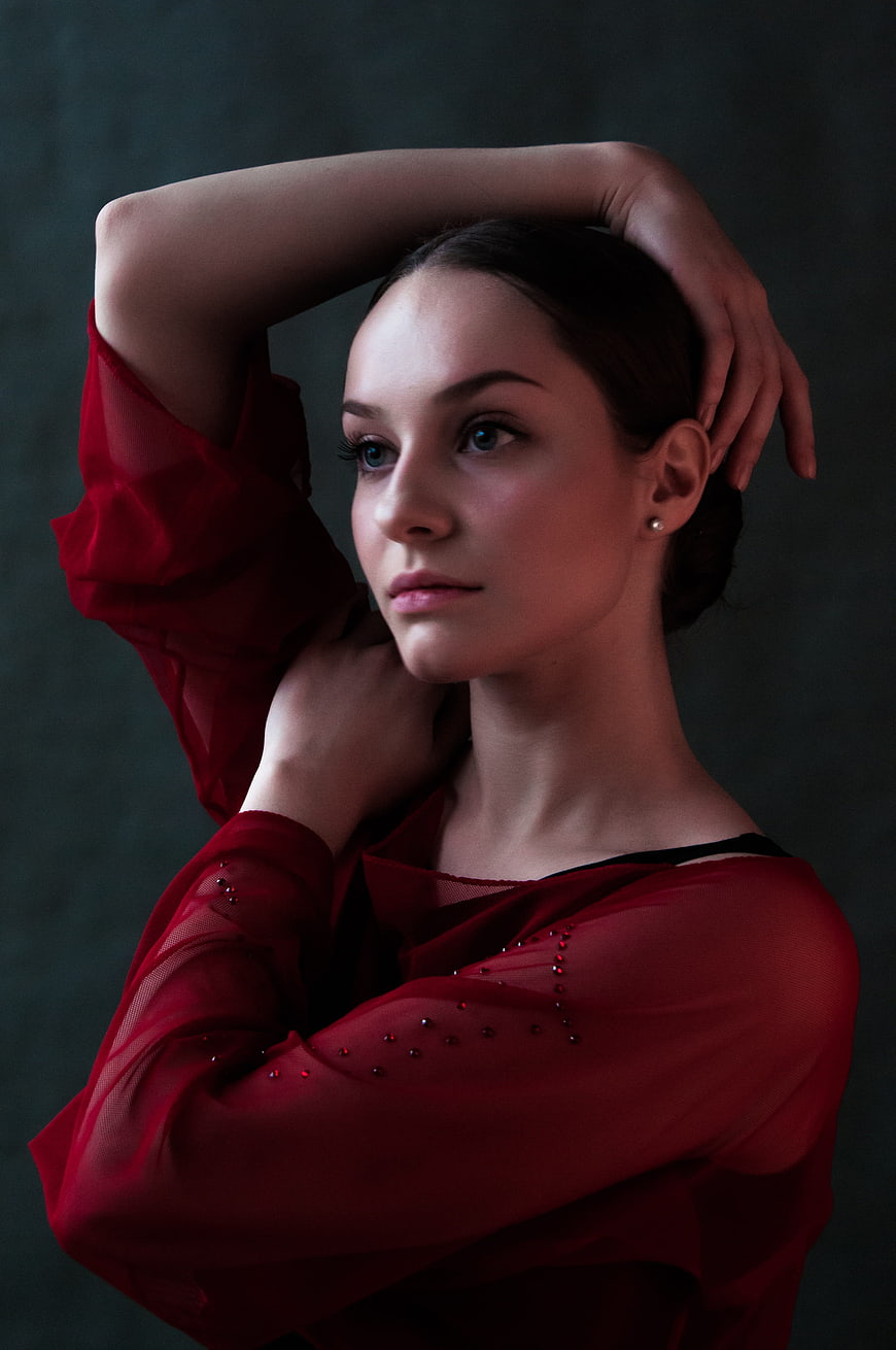 Elegant woman in red sheer blouse posing with hands behind head