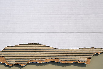 Torn white paper revealing corrugated cardboard texture background