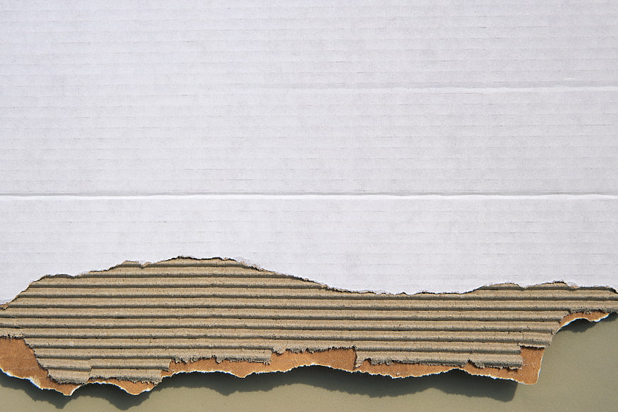 Torn white paper revealing corrugated cardboard texture background