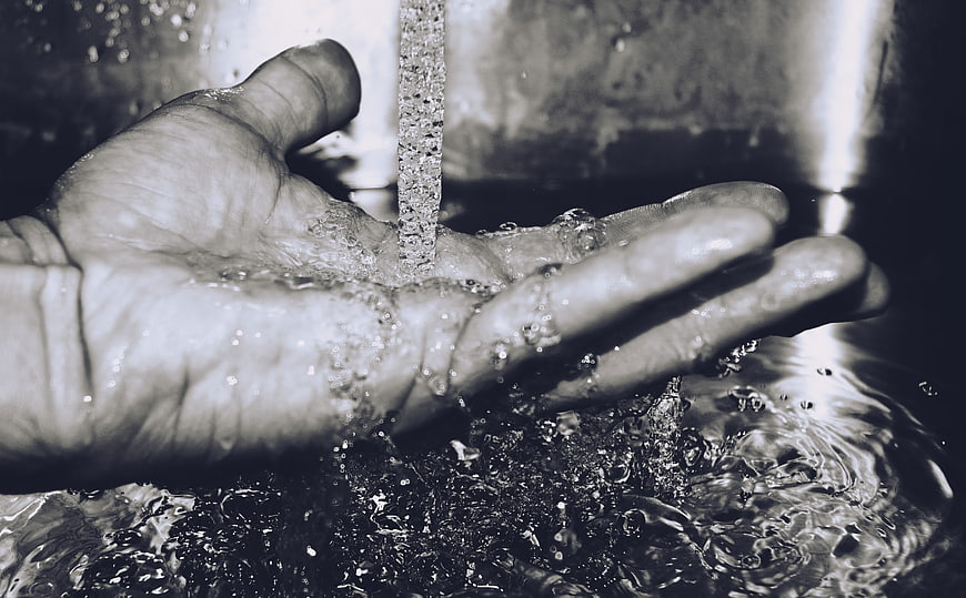 Close-up of hand washing under running water in black and white