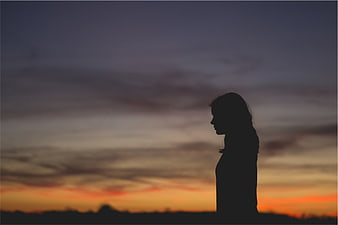 Silhouette of a woman against a colorful sunset sky
