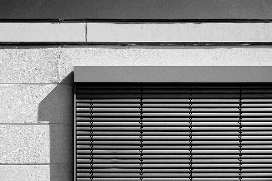 Black and white architectural detail of window blinds and wall