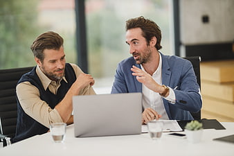Two businessmen discussing work on laptop in modern office