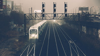White commuter train on tracks in foggy urban landscape