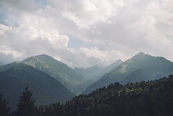 Majestic Green Mountain Range with Cloudy Sky and Forest