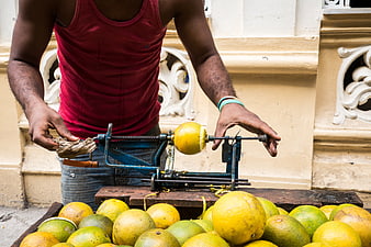 Man peeling yellow oranges with manual tool in Cuba