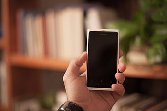 Hand holding white Nokia smartphone in office setting