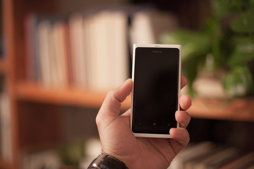 Hand holding white Nokia smartphone in office setting