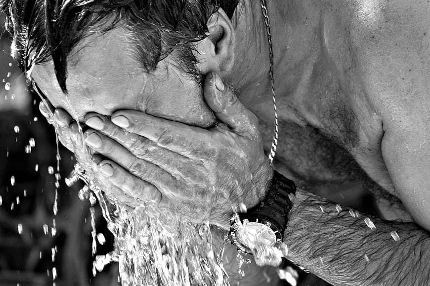 Man splashing cold water on face in black and white