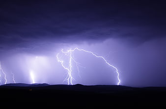 Dramatic Lightning Storm Over Dark Mountain Silhouette at Night