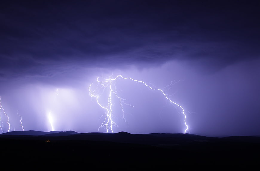 Dramatic Lightning Storm Over Dark Mountain Silhouette at Night