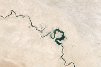 Aerial view of winding river cutting through vast arid desert landscape