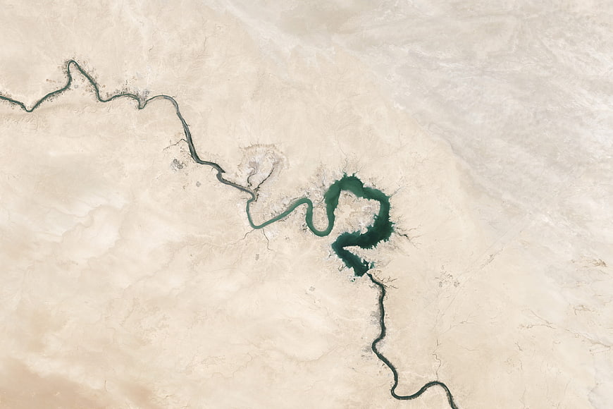 Aerial view of winding river cutting through vast arid desert landscape