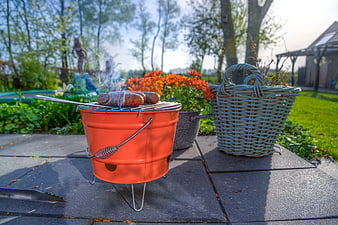Miniature orange bucket grill with sausages in a sunny garden