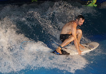 Man surfing on artificial wave pool with splashing water