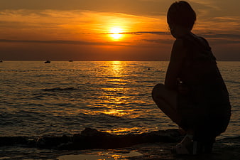 Silhouette of Woman Watching Golden Sunset Over Ocean