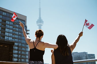 Two women waving Canadian flags on Toronto rooftop