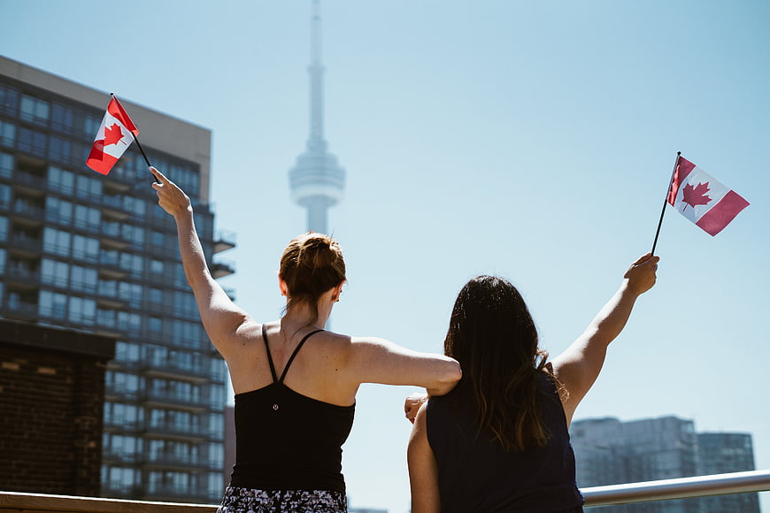 Two women waving Canadian flags on Toronto rooftop