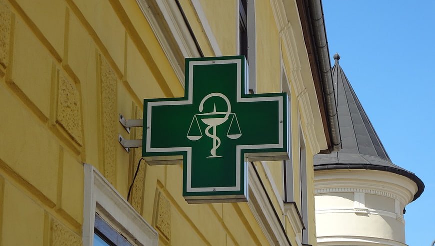 Green Pharmacy Cross Sign on Yellow Building Facade