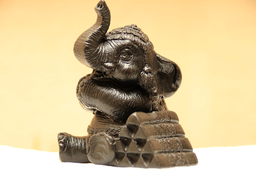 Bronze Ganesha Statue with Raised Trunk on Gold Background