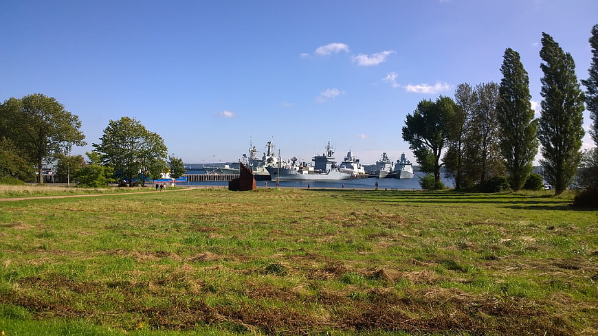 Naval ships docked in harbor with grassy park foreground