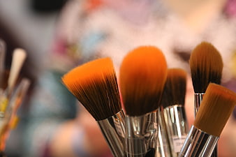 Close-up of orange makeup brushes with silver handles