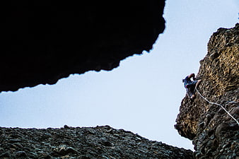 Rock Climber Scaling Cliff Face with Rope