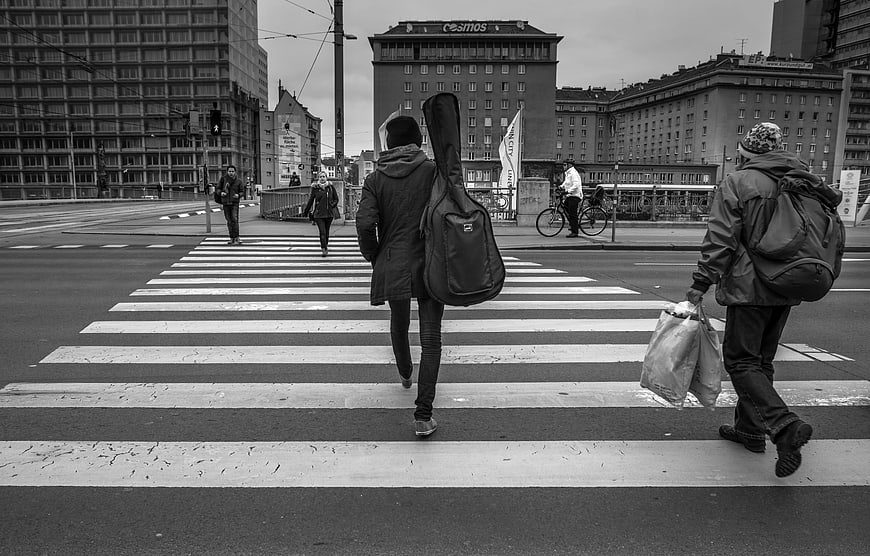 Pedestrians Crossing City Street with Guitar Case